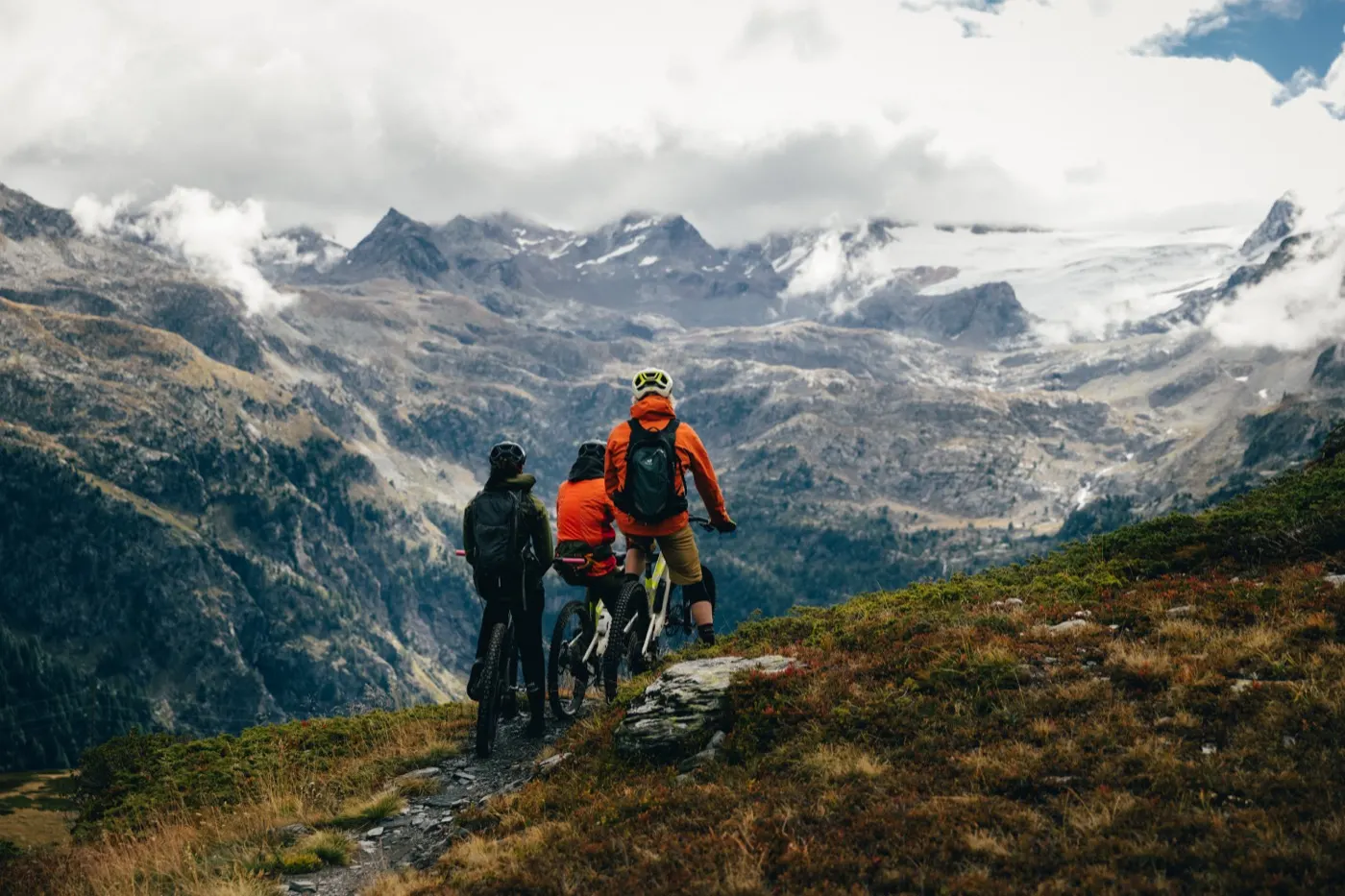 Three riders looking down at a glacier from a mountain trail